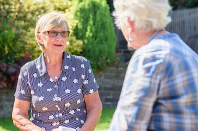 Two senior women talking in a garden