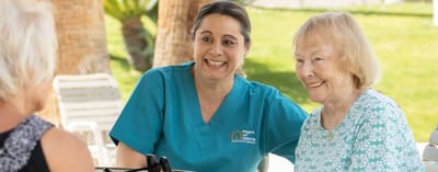Resident and caregiver smiling in an outdoor setting