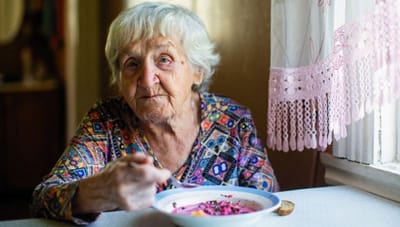 Elderly woman enjoying a meal at a table