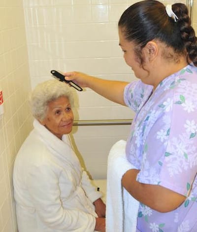 Staff styling hair for a resident in a care facility