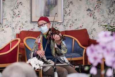 A musician performing for residents in a cozy common area
