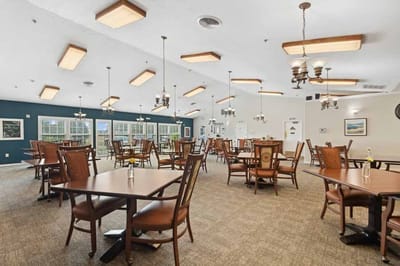 A dining room with tables and chairs set up for residents