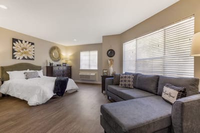 A well-furnished resident room with a bed and seating area