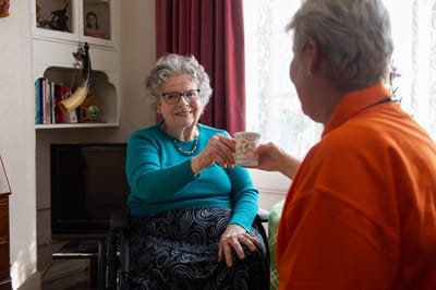 Resident enjoying a drink with staff in a cozy interior
