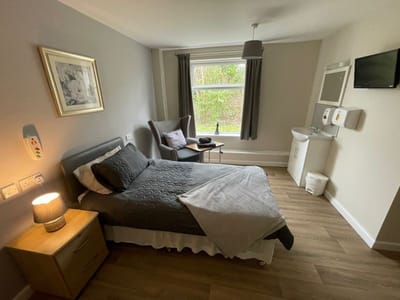 Brightly lit resident room with bed and chair