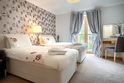 A well-decorated resident room with two beds and natural light