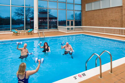 Residents participating in a water exercise class in an indoor pool