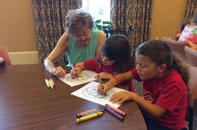 Resident coloring with children in activity room