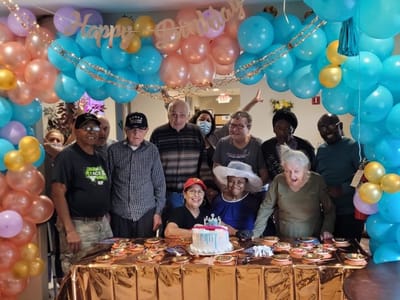 Residents celebrating a birthday with cake and balloons