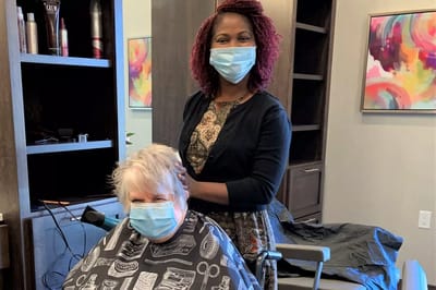 Stylist working on a resident's hair in the salon