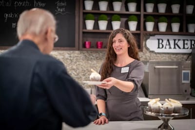 Staff serving dessert to a resident in the dining area