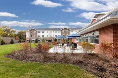 Outdoor patio area with seating next to a senior living facility