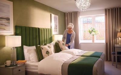 A resident arranging pillows in a cozy twin bedroom