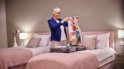 A resident unpacking clothes in a bedroom