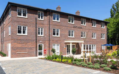 Exterior view of a senior living facility with gardens and seating