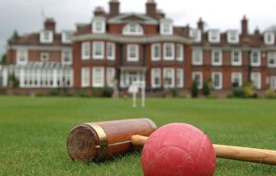 Croquet mallet and ball in front of a large building