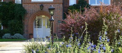 Building entrance with flower beds and lamppost