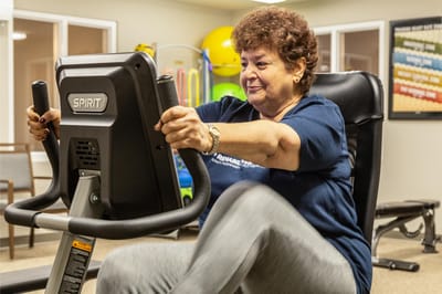Resident exercising on a stationary bike in the fitness area