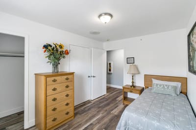 A cozy resident room with a bed and dresser