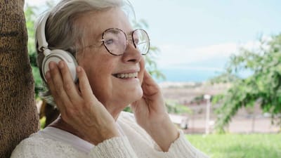 Elderly woman enjoying music outdoors with headphones