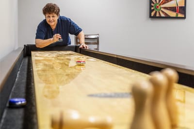 Resident playing shuffleboard in a common area