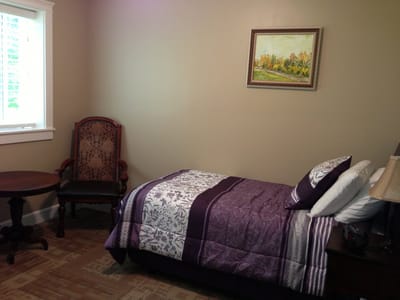 A cozy resident room with a bed and chair