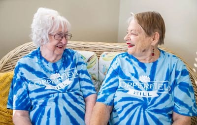 Two residents in matching t-shirts smiling together