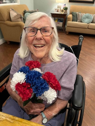 Resident smiling with flowers in a common area