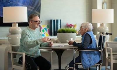 Two residents engaging in a card game in a common area