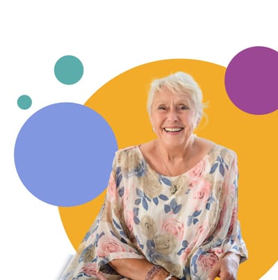An elderly woman smiling against a colorful background