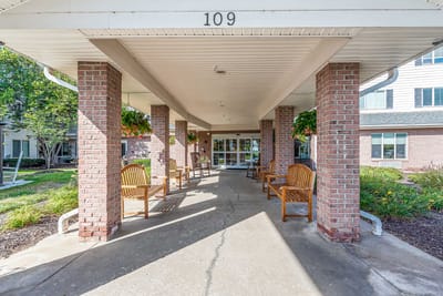 Covered entrance area with benches and landscaping