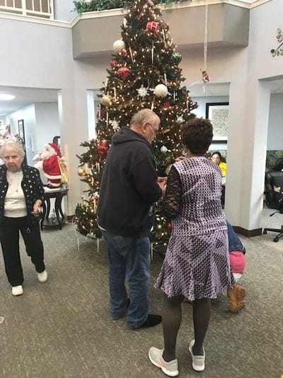 Residents enjoying Christmas activities around a decorated tree