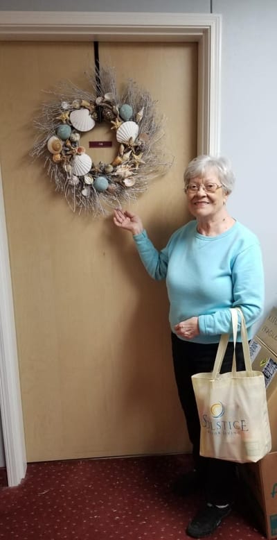 A resident displaying a decorative wreath by her door