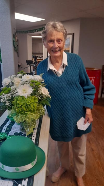 Resident smiling with a flower arrangement in a common area