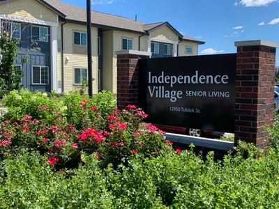 Signage of Independence Village with blooming flowers.