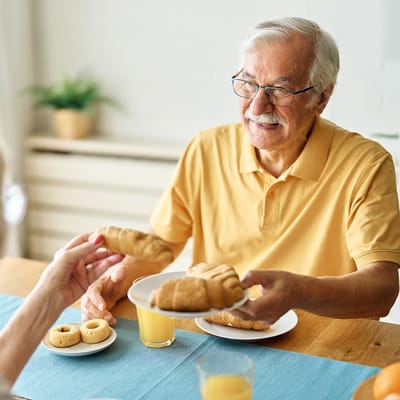 An elderly man smiling and being served food