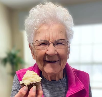 Resident happily holding a cupcake indoors