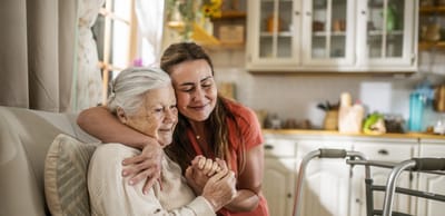 A caregiver embracing a senior resident in a bright room