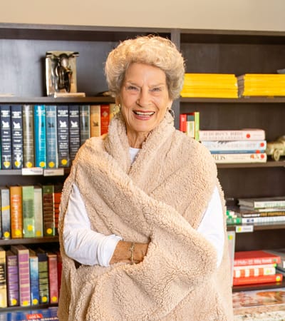 Smiling resident in a cozy living area with bookshelves