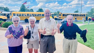 Residents enjoying a sunny day outdoors with school buses in background
