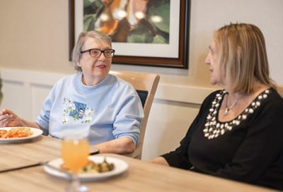 Residents enjoying a meal and conversation in a dining area
