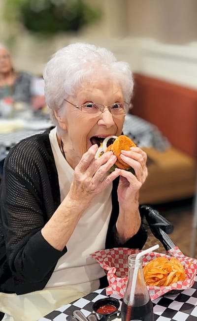 Resident enjoying a burger with fries in the dining area