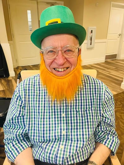 Resident dressed for a festive celebration with an orange beard and green hat.