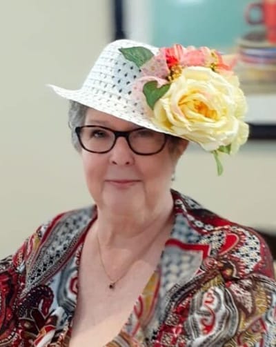 A resident wearing a decorative hat and smiling