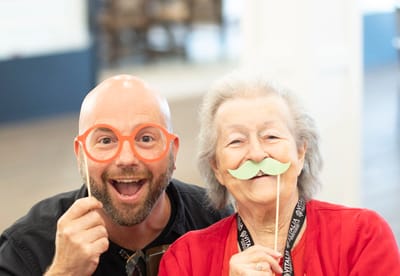 Resident and staff member having fun with props