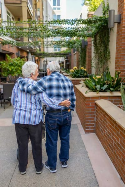 Elderly couple walking together in a garden path