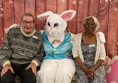 Two residents posing with the Easter Bunny in a festive setting.