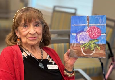Resident showing her painting in an activity room