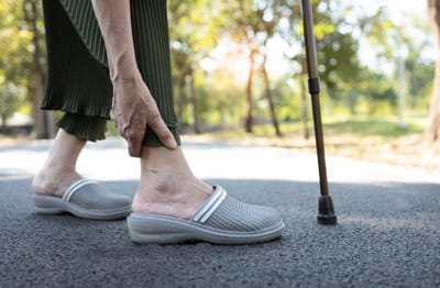 Senior using a cane while walking in a garden