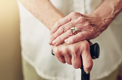 Close-up of elderly hands holding a cane